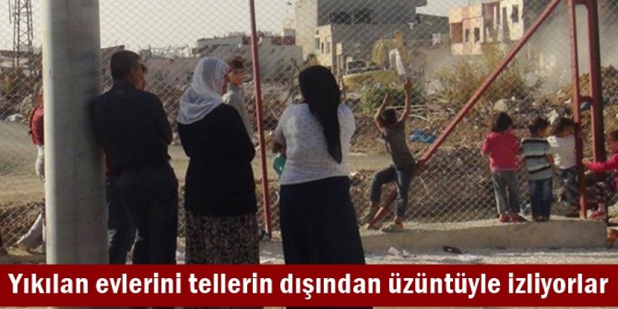 Yıkılan evlerini tellerin dışından üzüntüyle izliyorlar