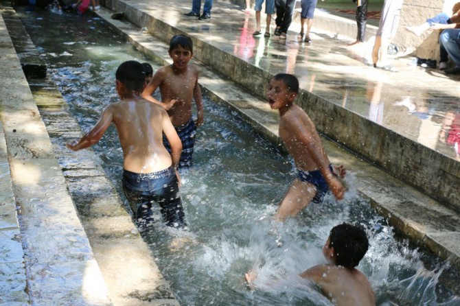 Şanlıurfa'da çocuklar cami avlusundaki suya girerek serinliyor
