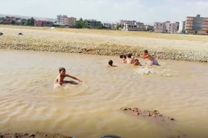 Batman’da sıcaklardan bunalan çocuklar çamurlu suda yüzdüler