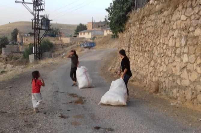 Çocuklarda çevre temizliği bilincini geliştirmek için onlarla birlikte çöp topluyor