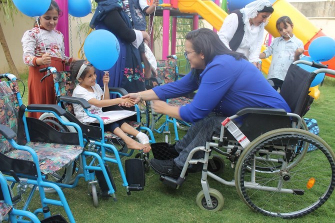 Disabled woman presents wheelchairs to 72 disabled people