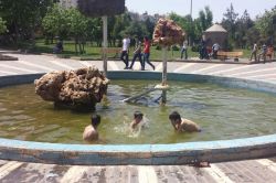 Çocuklar kirli süs havuzlarında serinliyor